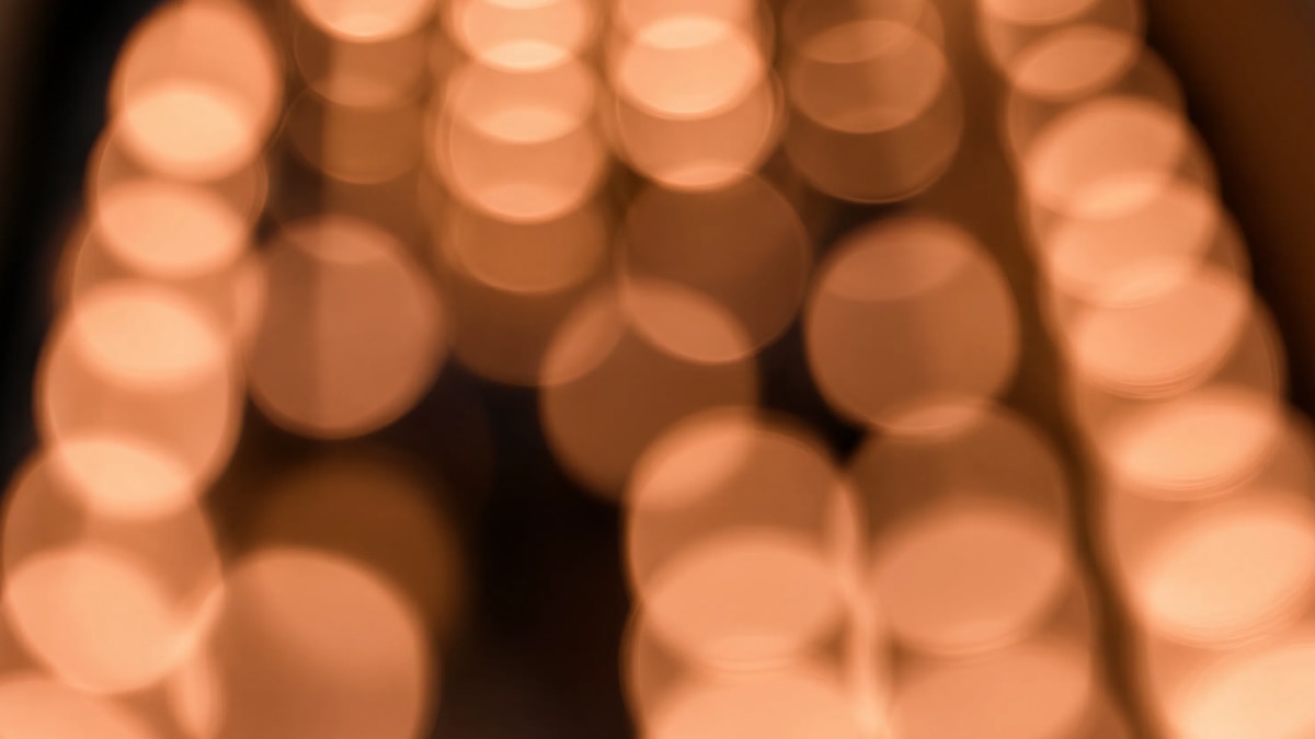Abstract warm orange bokeh lights with soft circular highlights on a dark background.