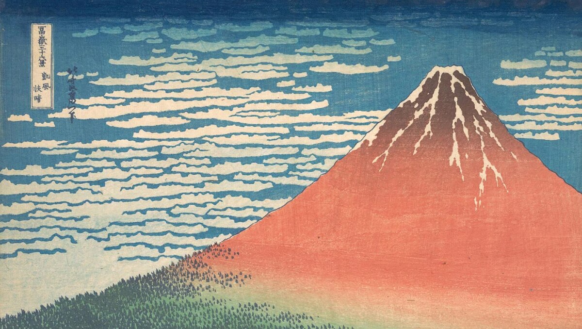 Japanese woodblock print of Mount Fuji with red slopes, snowcapped peak, blue sky and white clouds; vertical Japanese text at left.