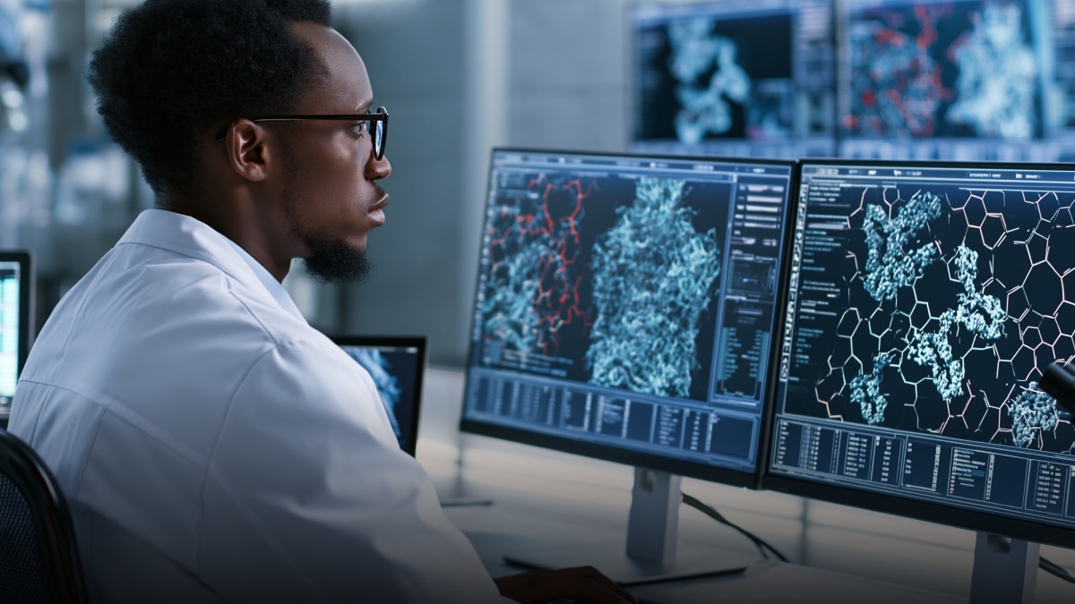 Scientist in white lab coat analyzing molecular data and protein structures on dual monitors.