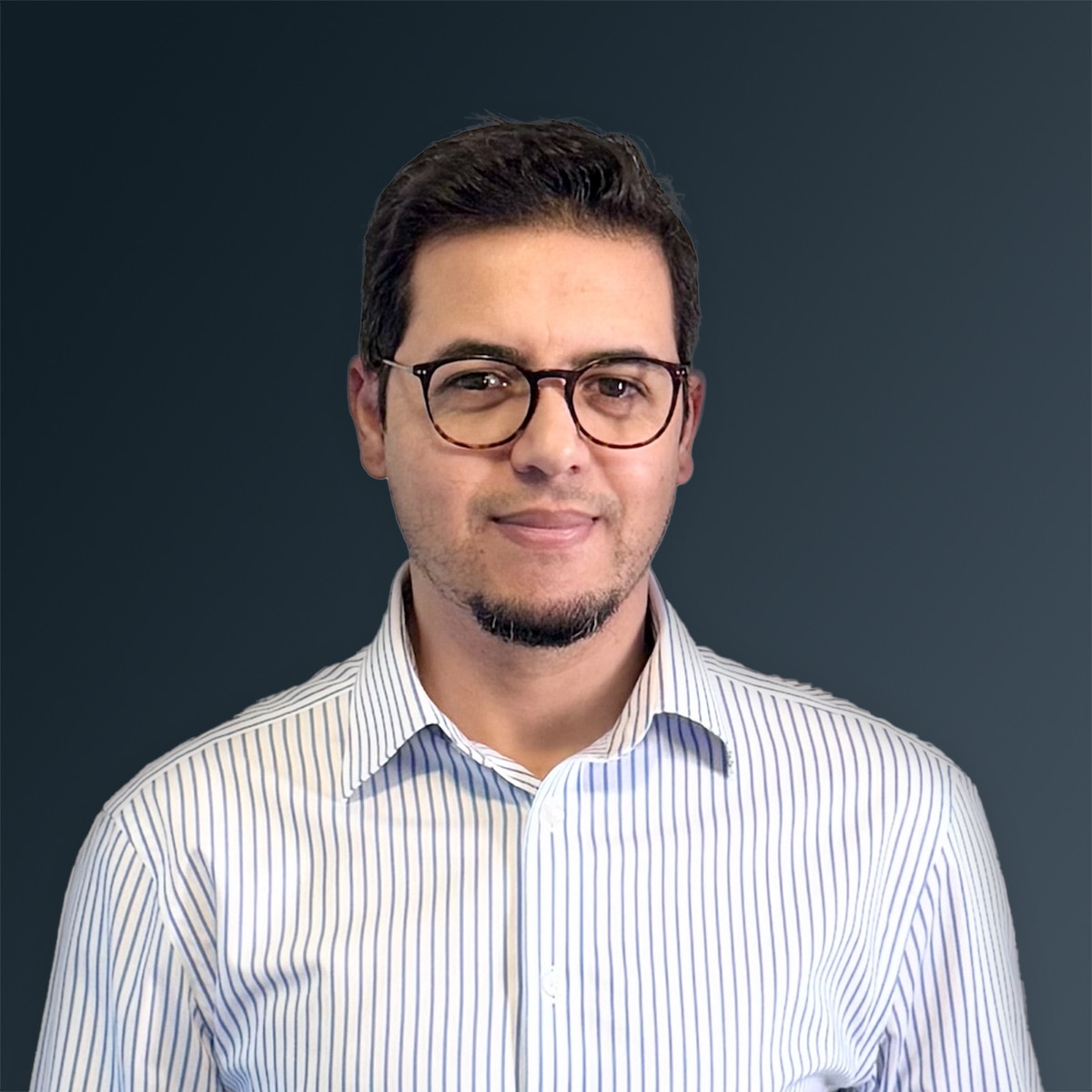 Man with glasses wearing a white and blue striped collared shirt against a dark gradient background.
