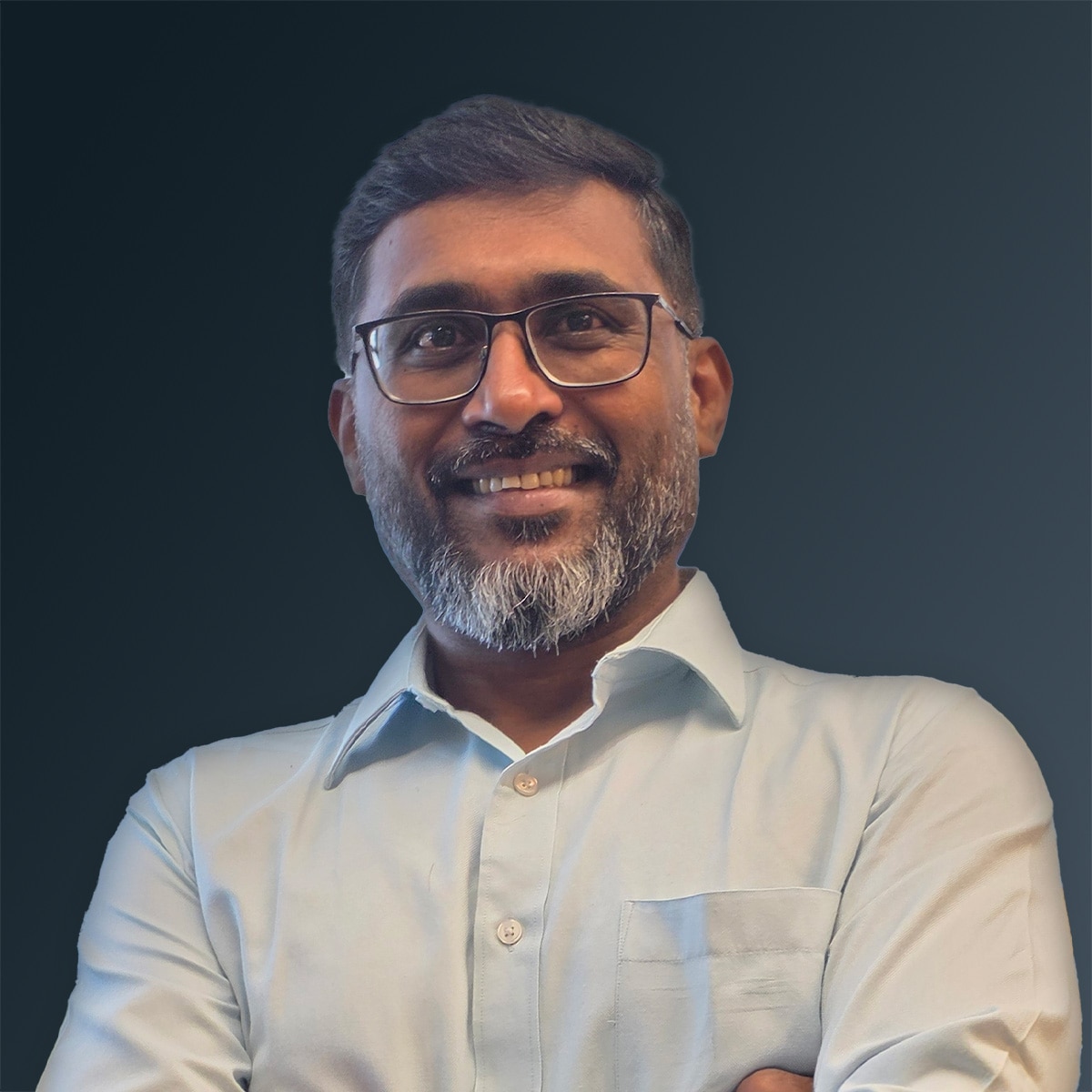 Man wearing glasses and a light collared shirt smiling against a dark gradient background.