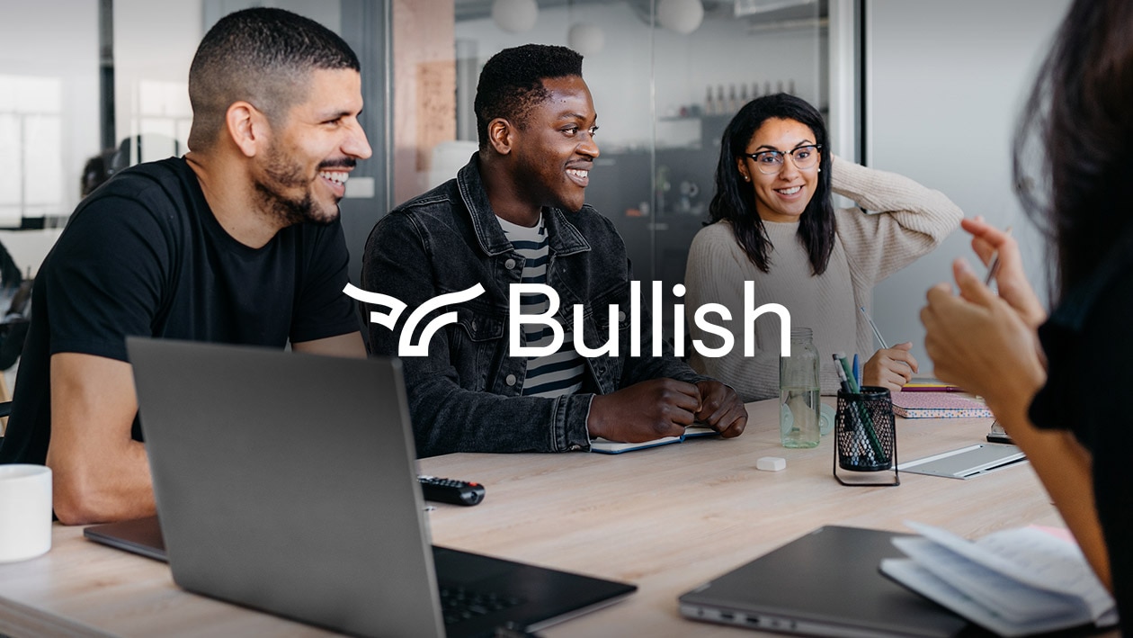 Financial Services: Bullish Image showing Bullish logo in white color with people sitting at the desk holding a busines meeting.