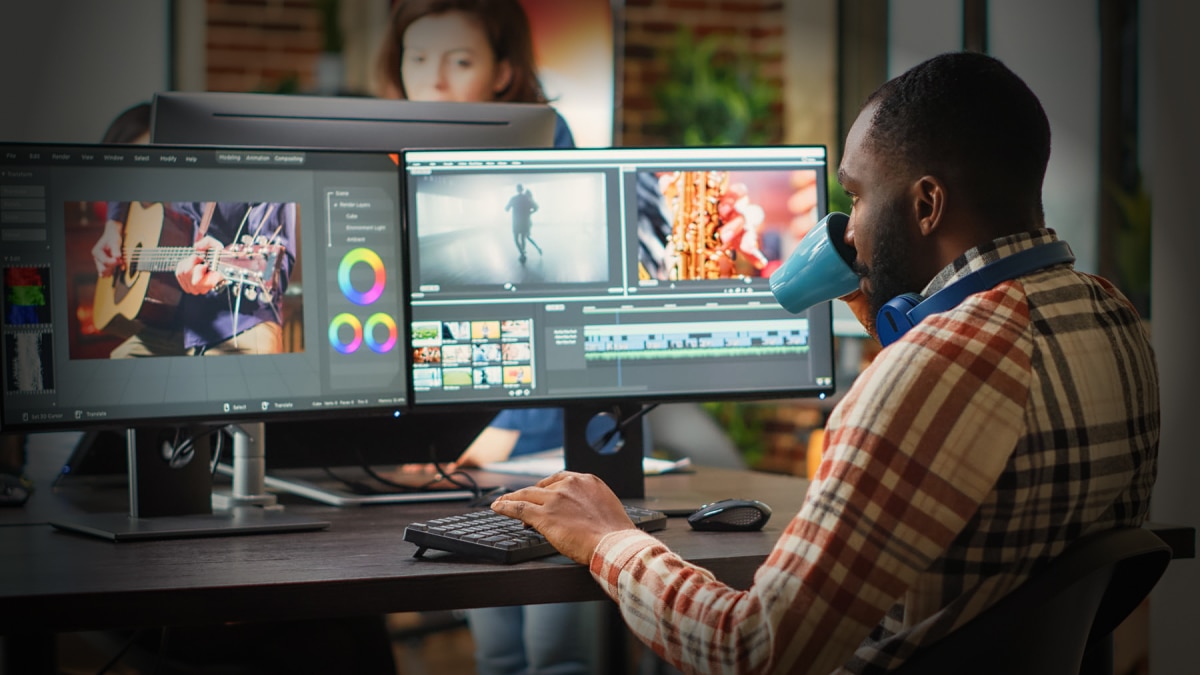 man looking at computer monitors editing videos