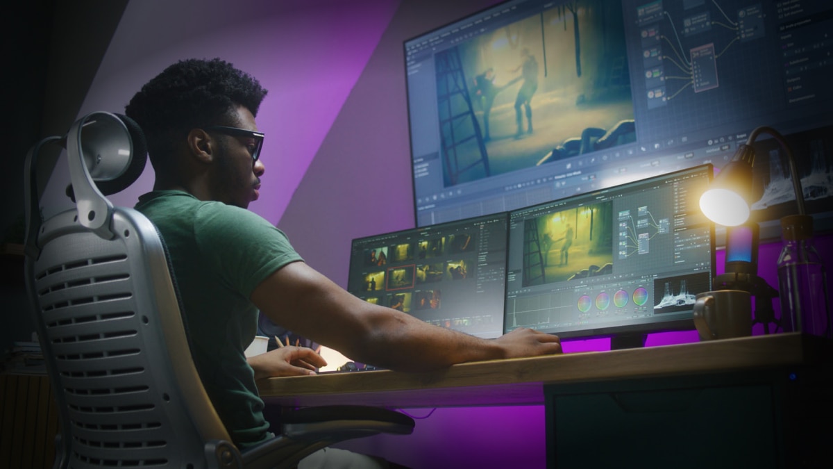 man looking at computer monitors editing videos