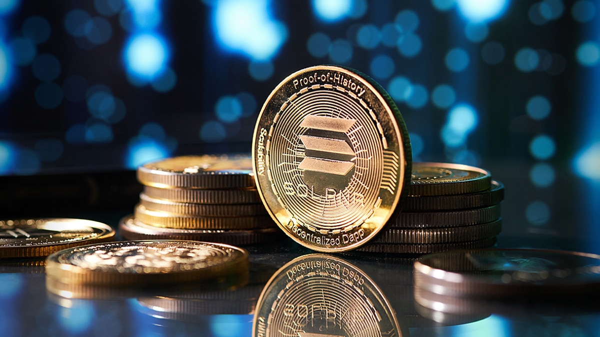 Stack of gold Solana coins with reflective surface and blurred blue bokeh background.