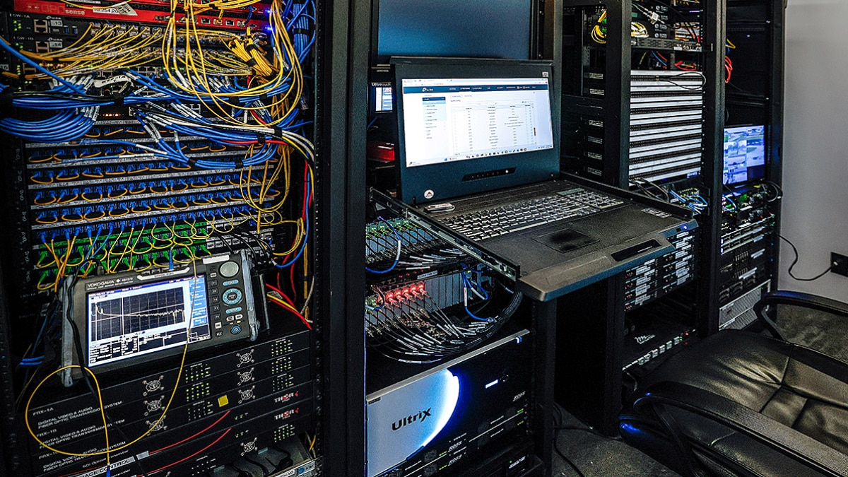Inside view of the IMSA Technology Center showing servers, network cabling, and monitoring equipment powered by Lenovo and AMD systems.