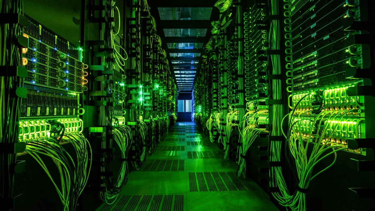 Long aisle of servers glowing green with dense wiring and LEDs along both racks.