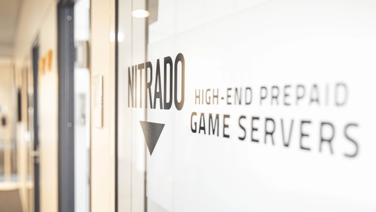 Office glass door with visible text “NITRADO High-End Prepaid Game Servers” in black lettering.