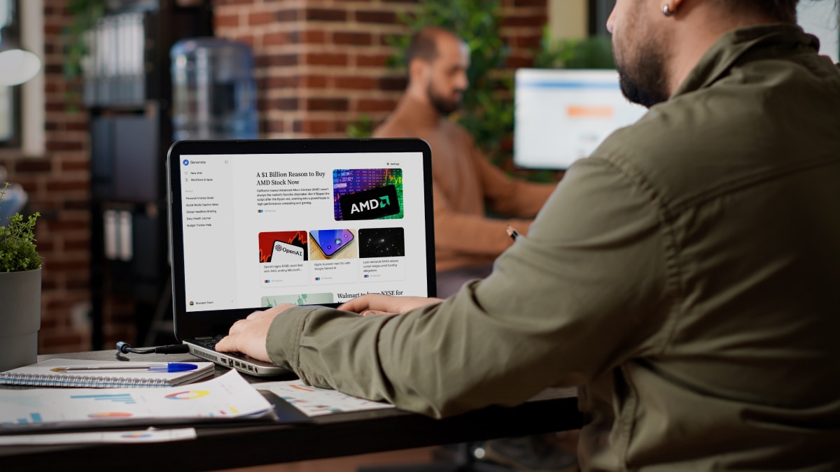 Person using a laptop displaying an AI and technology news dashboard at a shared workspace table.