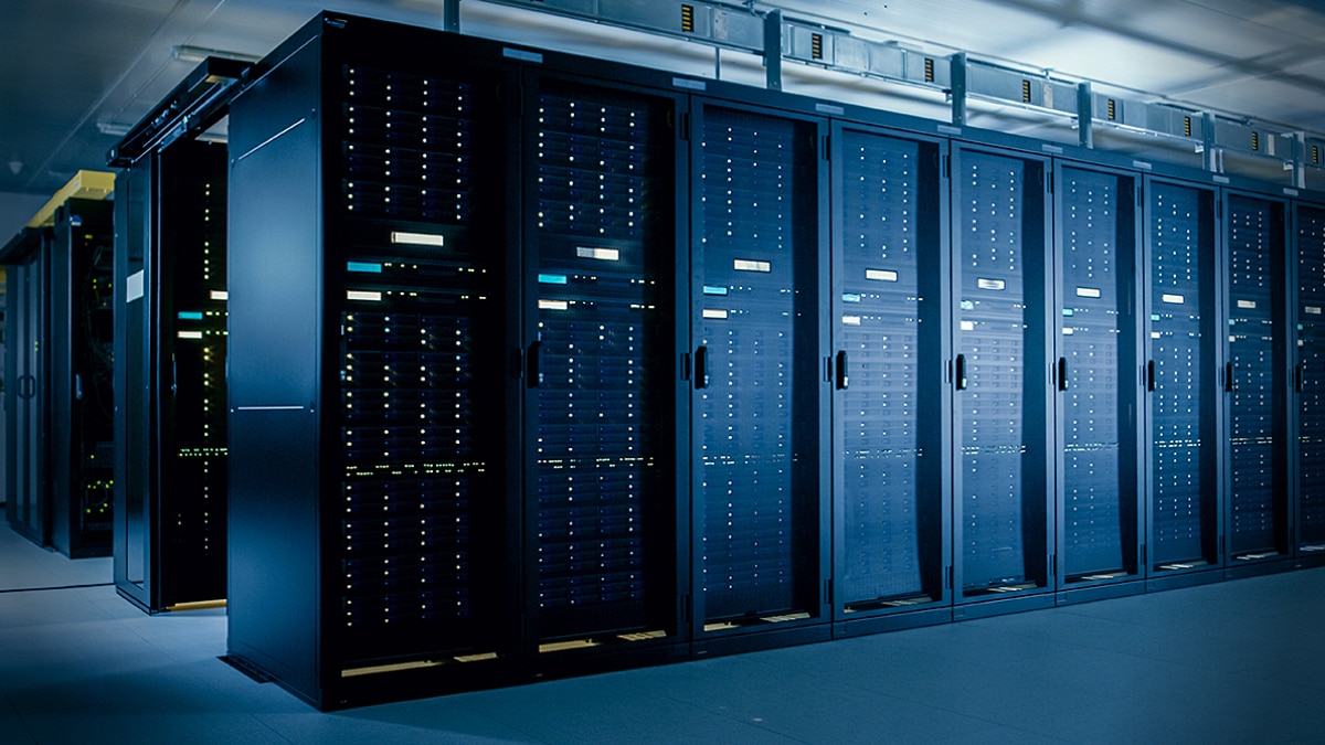 Row of blue-lit server racks inside a data center with visible status lights and cooling infrastructure.