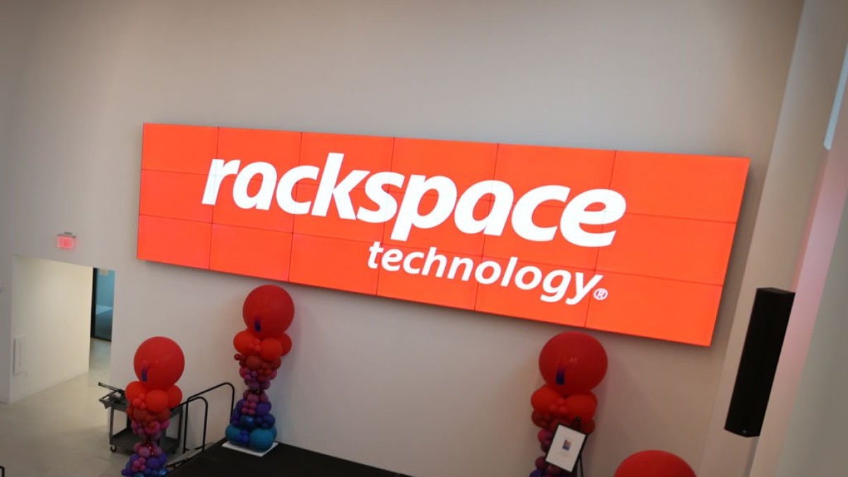 Two IT engineers examining illuminated server racks and cabling in a data center aisle.
