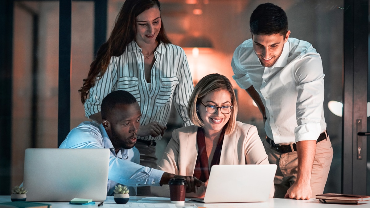 Wide view of operations floor with employees working at computer stations under large monitoring screens.