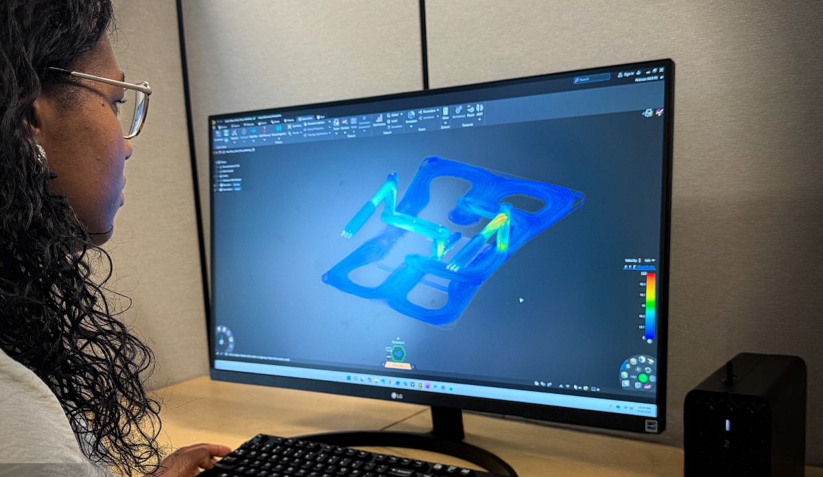 Person at desk viewing Ansys fluid simulation on widescreen monitor with keyboard and workstation setup