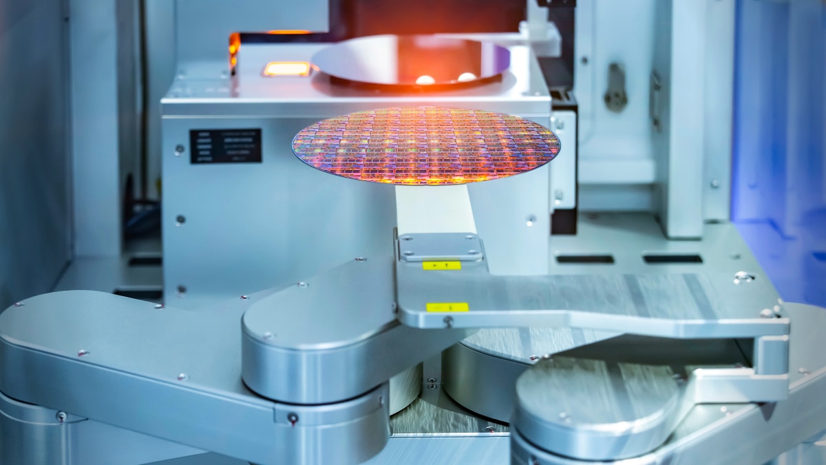 Automated semiconductor tool handling silicon wafer under orange light in chip fabrication equipment