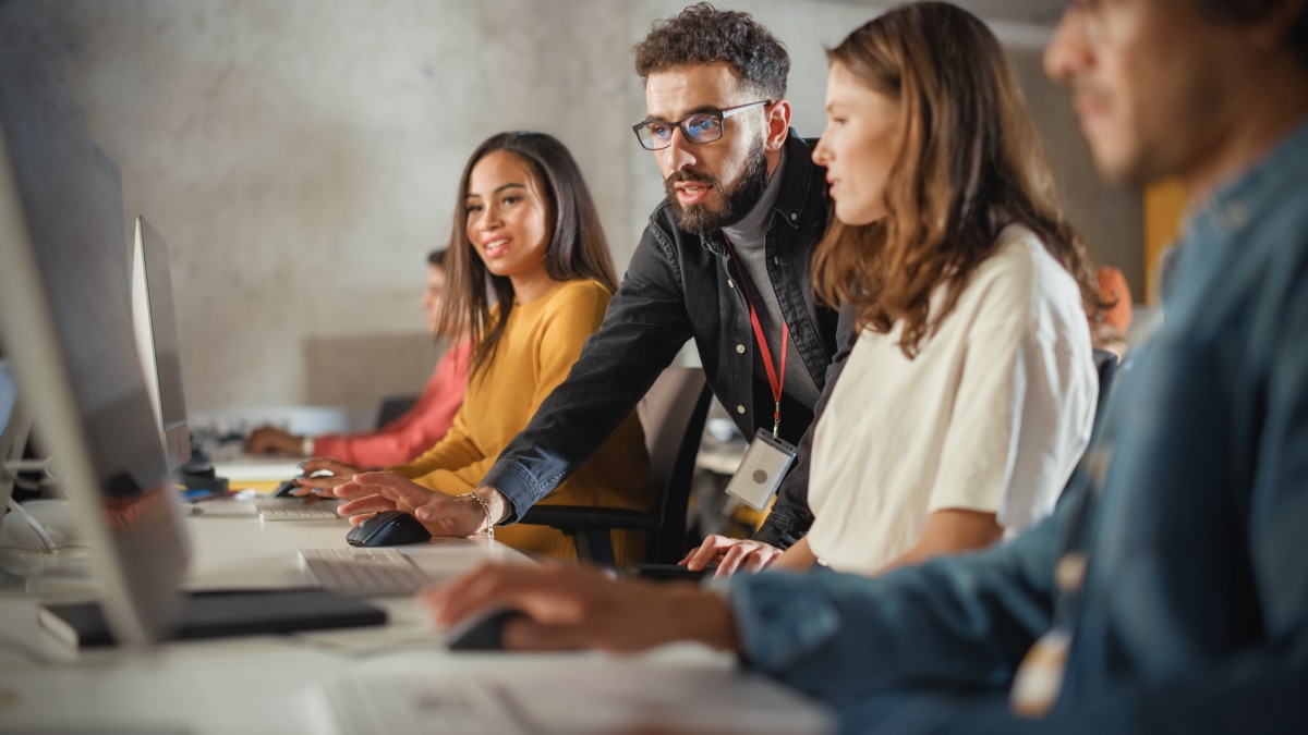 Team of professionals collaborating at desktop computers in a modern office workspace.