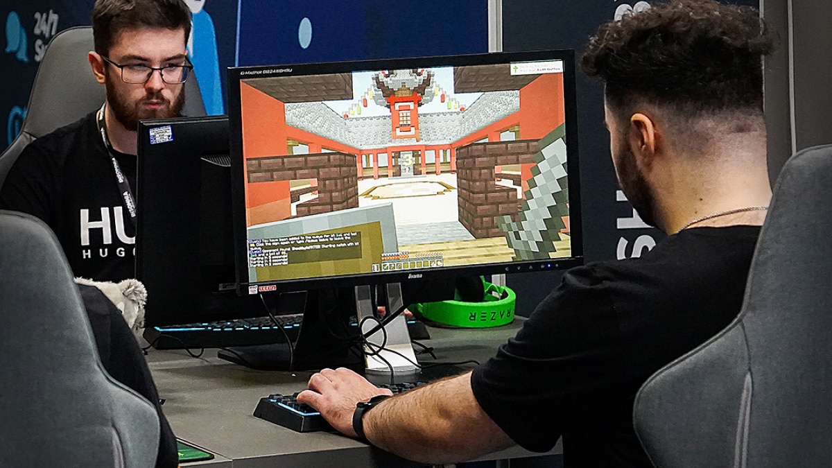 Gamers seated at desktop computers playing a block-style video game at a gaming event.