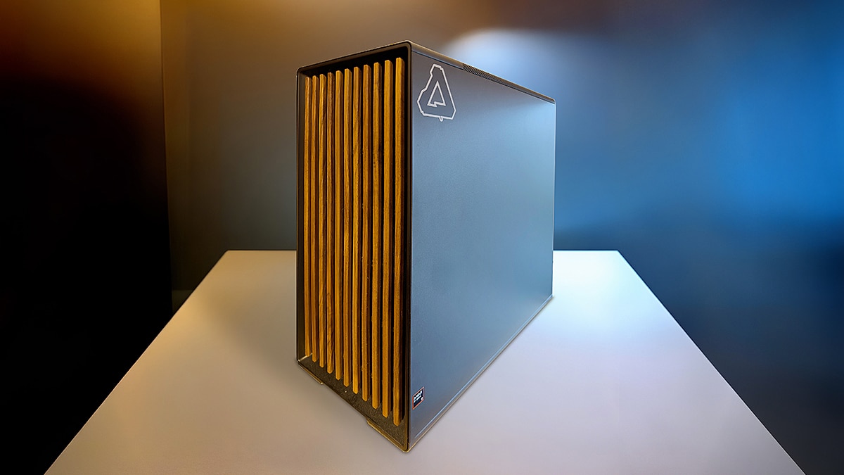 Black desktop computer tower with a gold slatted front panel on a white table against a blue and amber background.