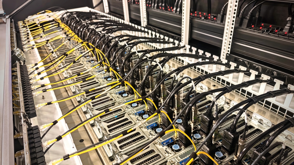 Dense server compute cluster with rows of connected black and yellow cables in a data center rack.