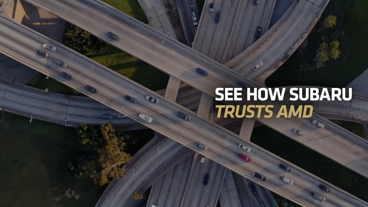 Aerial view of a multi-level highway interchange with cars in motion and on-image text “SEE HOW SUBARU TRUSTS AMD.”