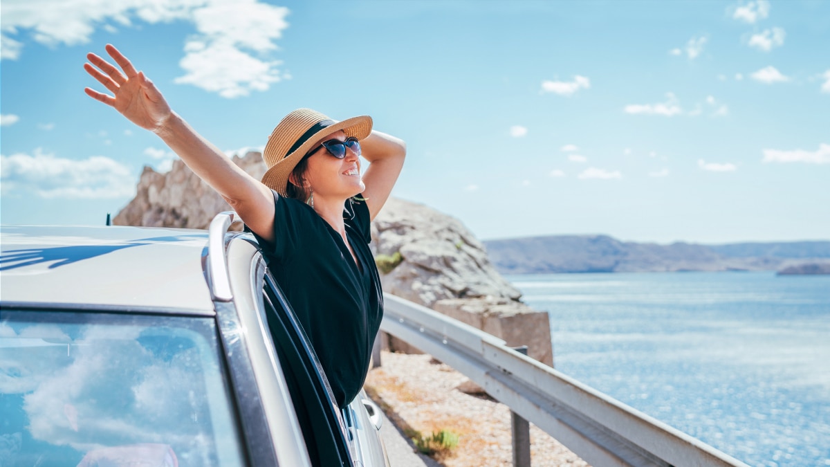 Couple sitting on mountain rocks enjoying a sunset view over a bay and coastal landscape, symbolizing relaxation, travel, and work-life balance.