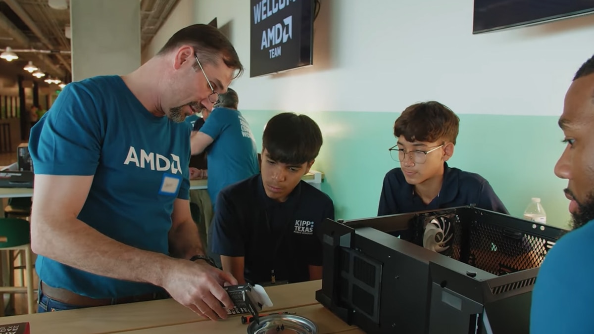 An AMD employee teaches students from KIPP Texas how to assemble a computer during an AMD community outreach workshop, fostering STEM education and hands-on technology learning.