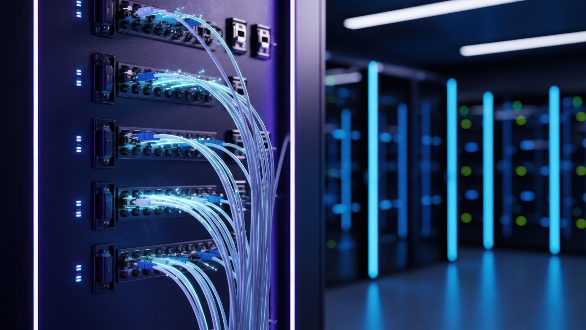Close-up of fiber optic cables connected to server ports with blue lighting in data center environment