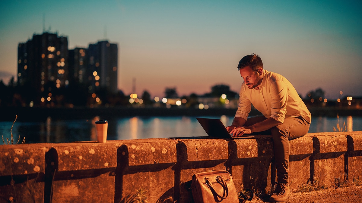 Man working on laptop near city river