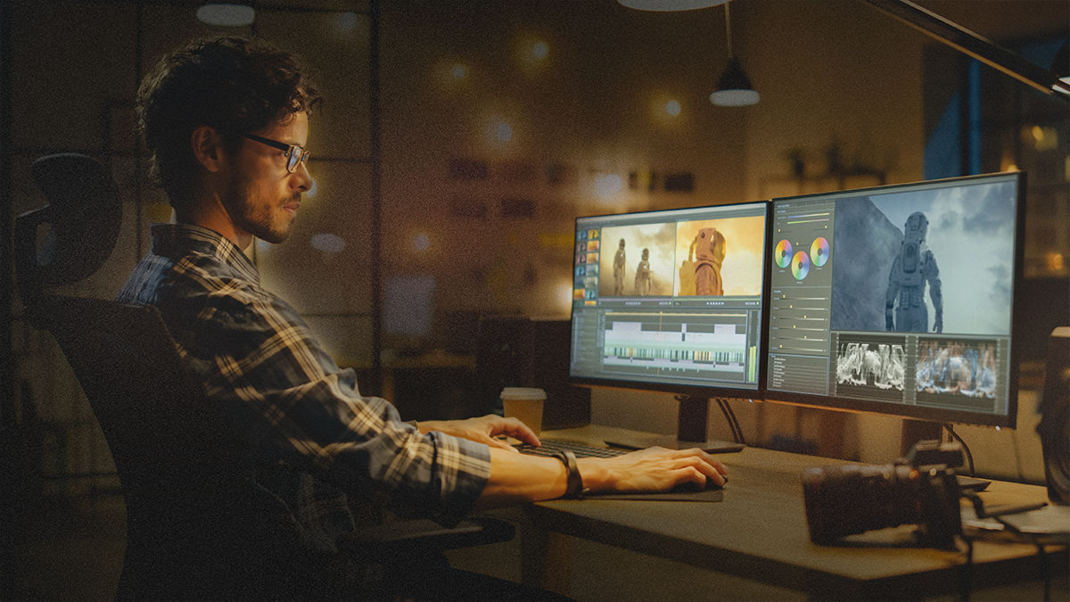Graphic designer working on desktop computer and looking at two screens