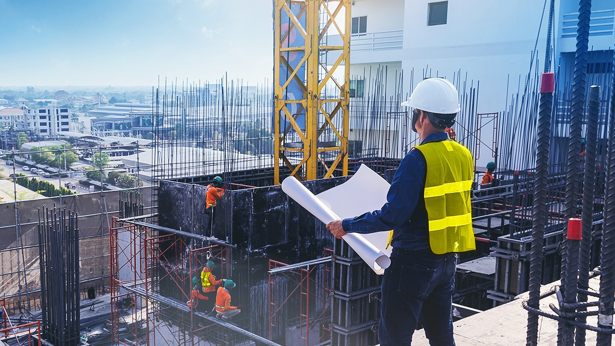 Civil architect engineer inspecting and working outdoors building side with blueprints