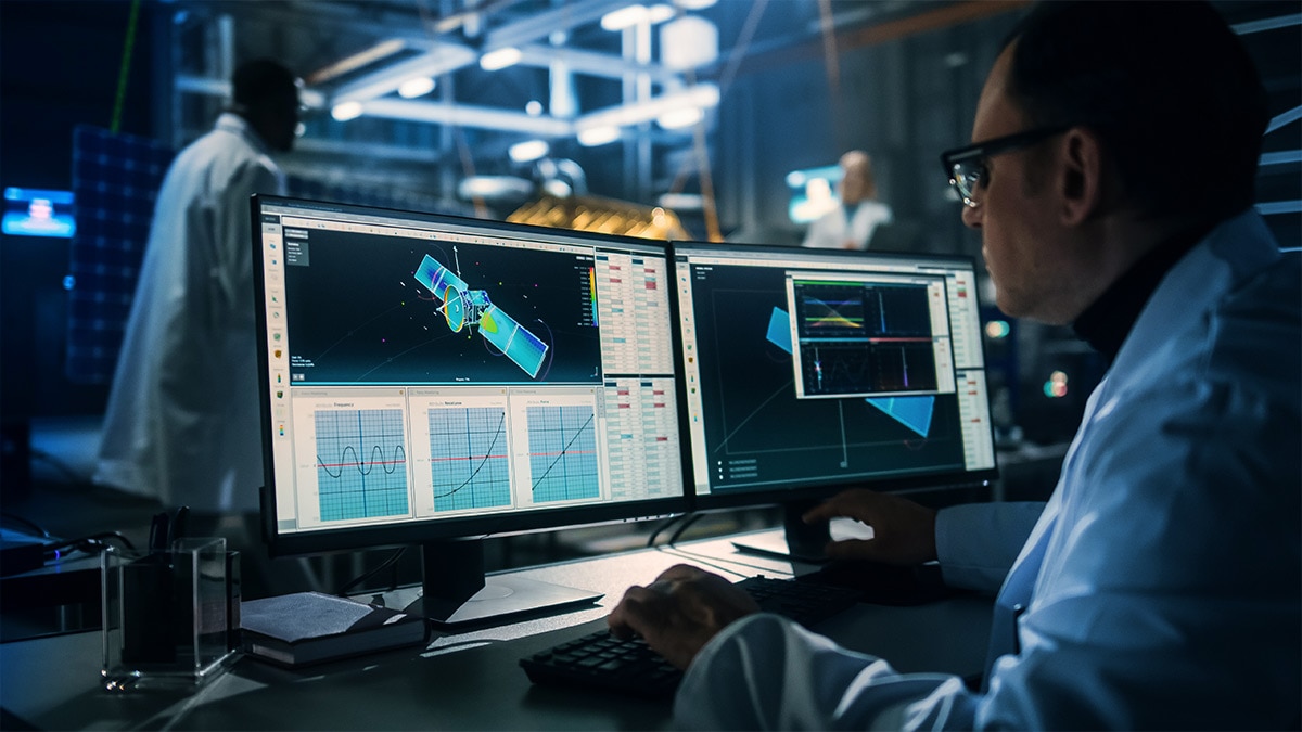 Male Engineer Uses Computer while Working on Satellite Construction