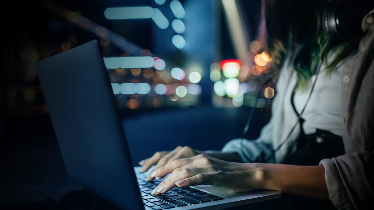 Woman using a laptop with night cityscape background Woman using a laptop with night cityscape background