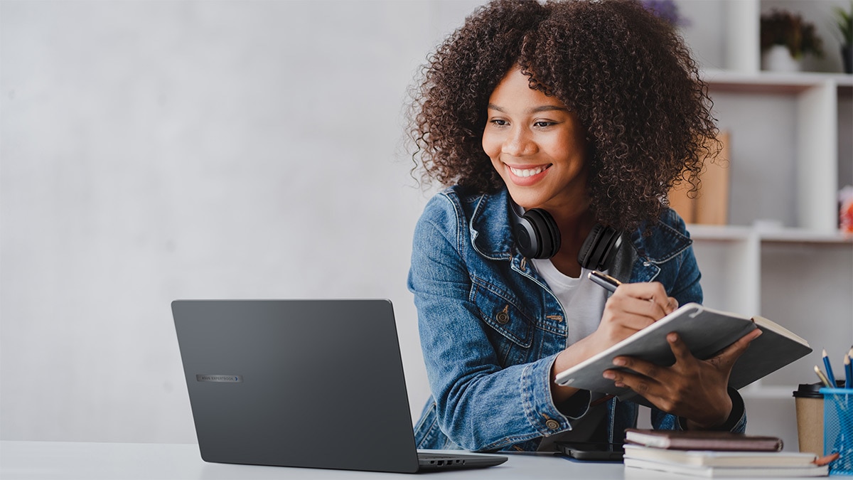 Woman working on a laptop, taking notes Woman working on a laptop, taking notes