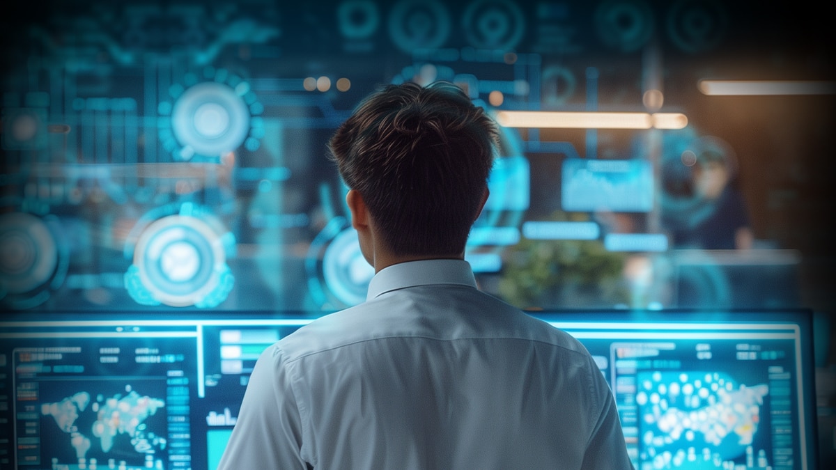 Person in white shirt monitors digital dashboards with analytics on multiple blue data center screens.