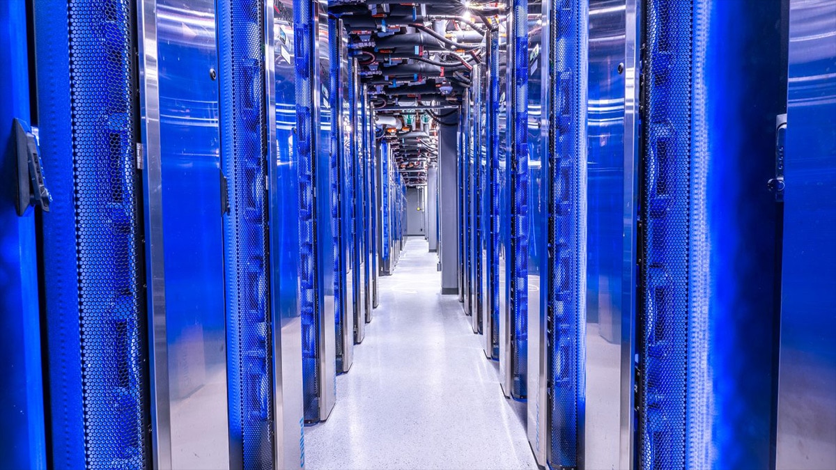Long aisle between blue server racks in a modern data center with overhead cabling
