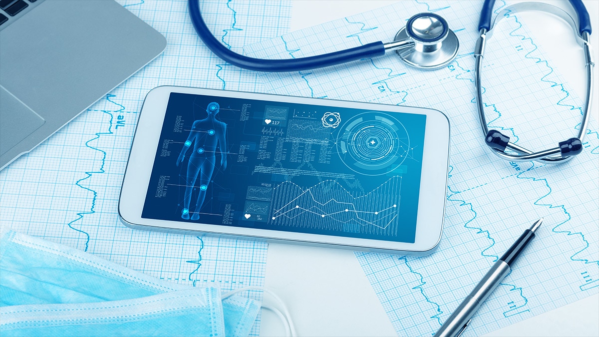 Tablet displaying a digital patient health dashboard with charts and body diagram beside a stethoscope