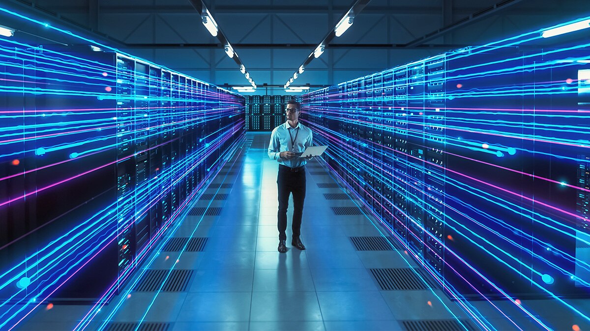 Man with laptop in server room with fast data transfer