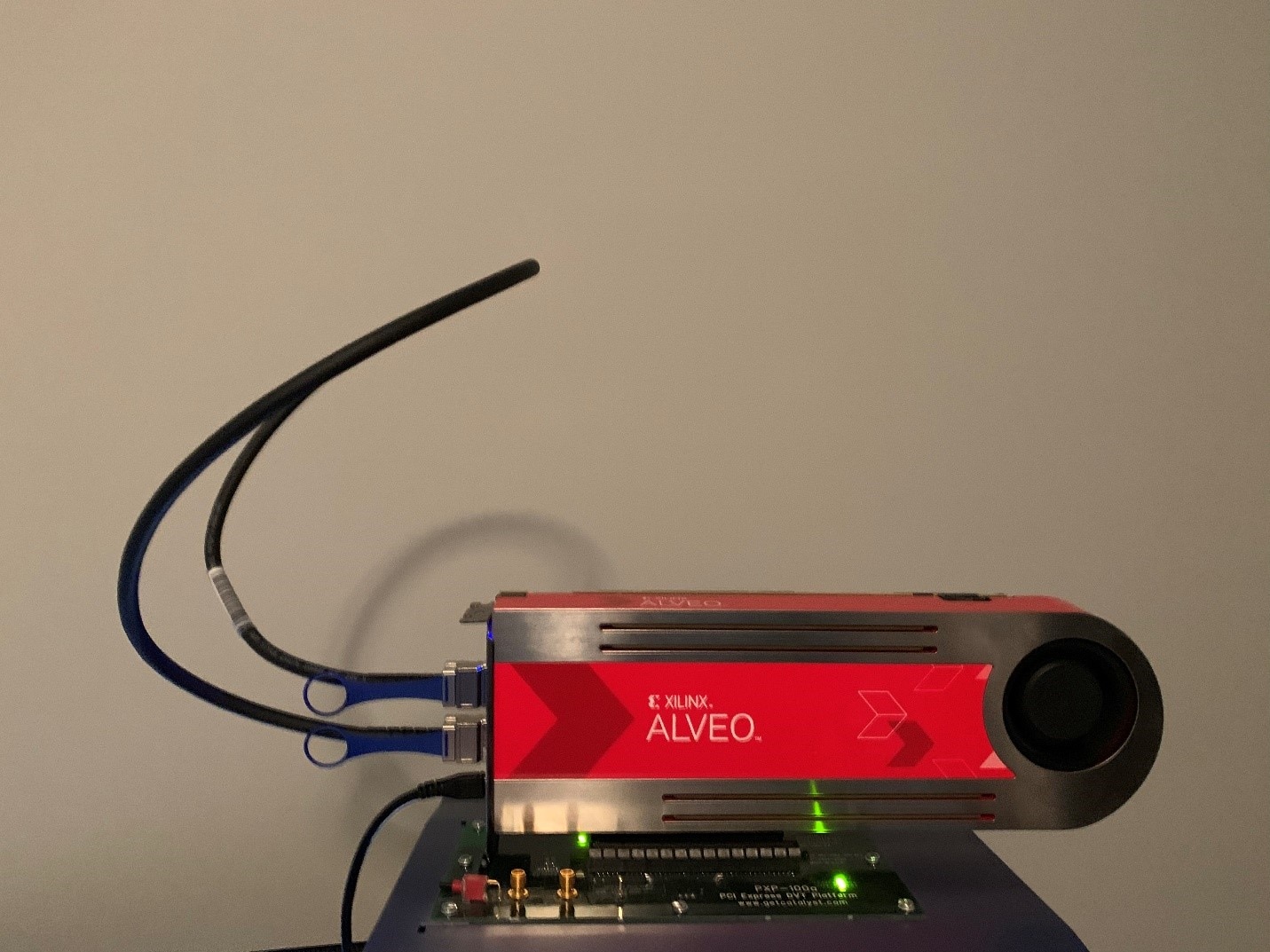 Red Xilinx Alveo accelerator card with cooling fan and multiple cables attached, powered on.